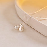 A miniature silver Lemon charm and Pear  charm on a silver rolo chain.